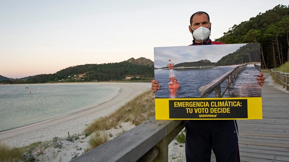 Un activista de Greenpeace sujeta un cartel en el que alerta de la emergencia climática