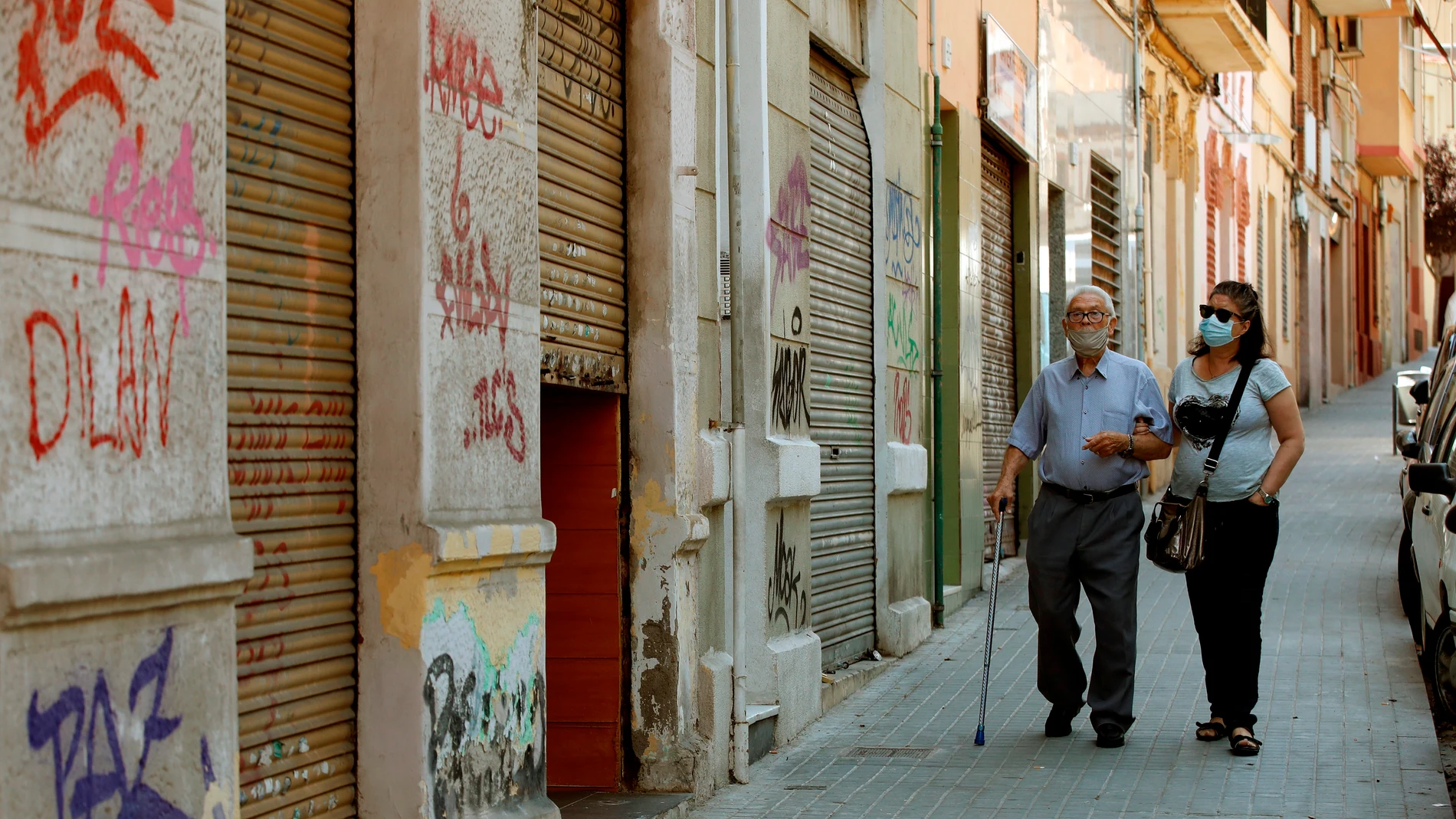 Una mujer acomapaña a su padre por una calle del barrio de la Torrassa