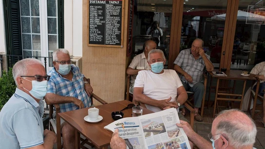 Un grupo de amigos tomando un café en un bar con la mascarilla puesta Un grupo de amigos tomando un café en un bar con la mascarilla puesta