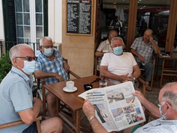 Un grupo de amigos tomando un café en un bar con la mascarilla puesta Un grupo de amigos tomando un café en un bar con la mascarilla puesta