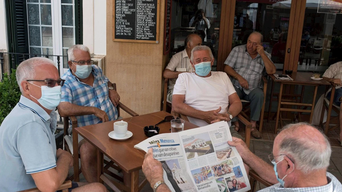 Un grupo de amigos tomando un café en un bar con la mascarilla puesta Un grupo de amigos tomando un café en un bar con la mascarilla puesta