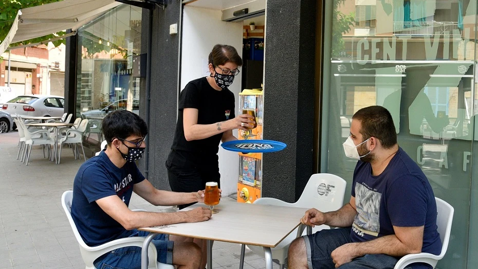 Imagen de dos jóvenes con mascarilla en una terraza de Lleida