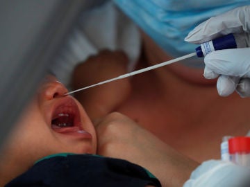 Un sanitario hace un test PCR a un bebé Un sanitario hace un test PCR a un bebé