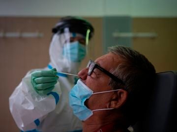 Una profesional sanitaria realiza una prueba PCR a un paciente en el CAP Raval Nord de Barcelona