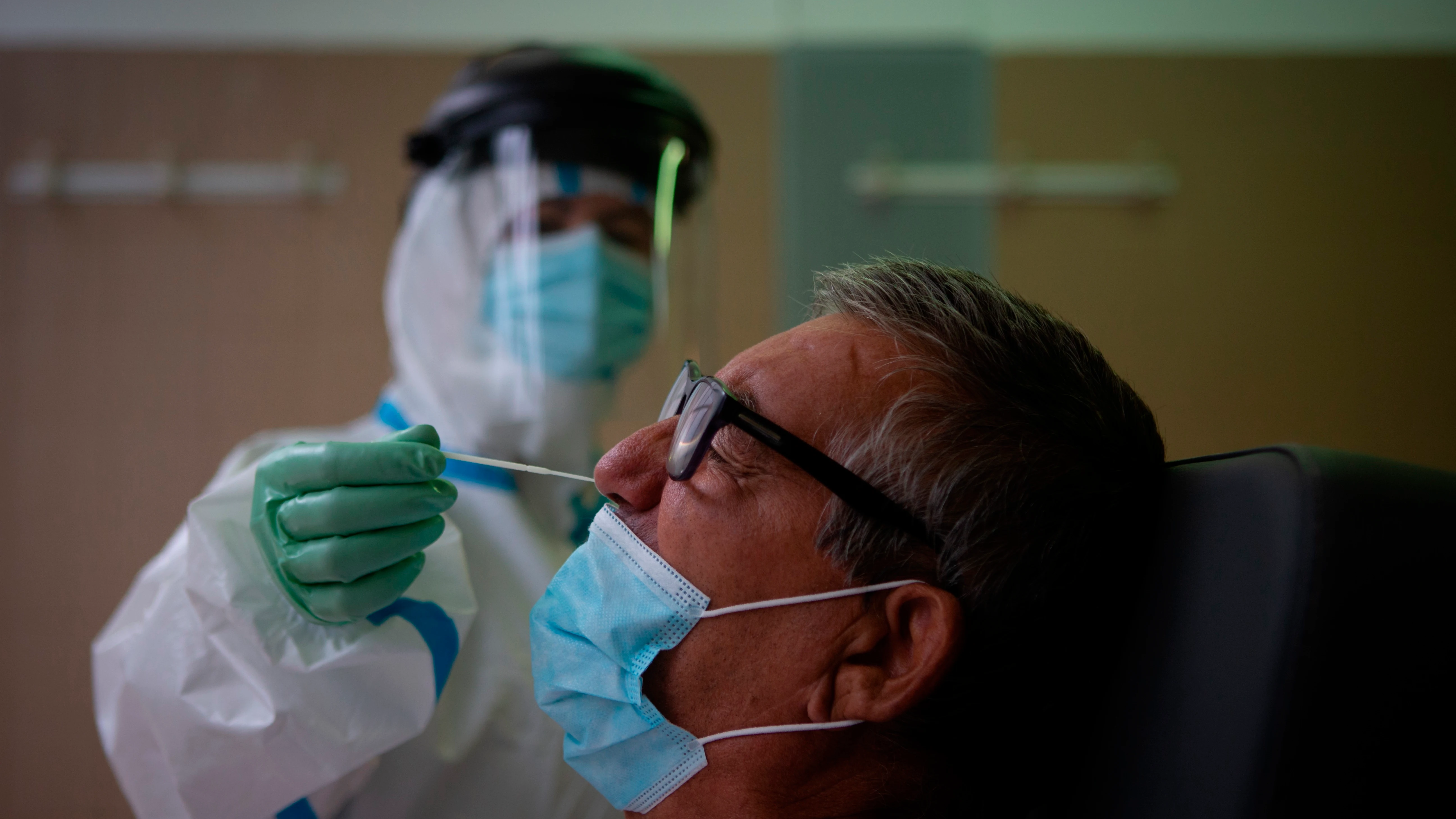 Una profesional sanitaria realiza una prueba PCR a un paciente en el CAP Raval Nord de Barcelona