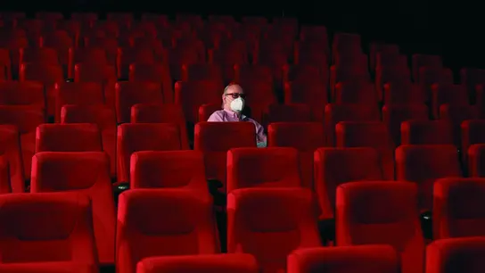 Un espectador espera el comienzo de la película en una sala de cine casi vacía Un espectador espera el comienzo de la película en una sala de cine casi vacía