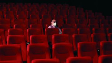 Un espectador espera el comienzo de la película en una sala de cine casi vacía