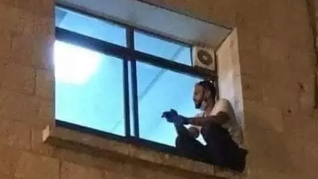 El joven palestino subido a la ventana del hospital para despedirse de su madre tras el cristal