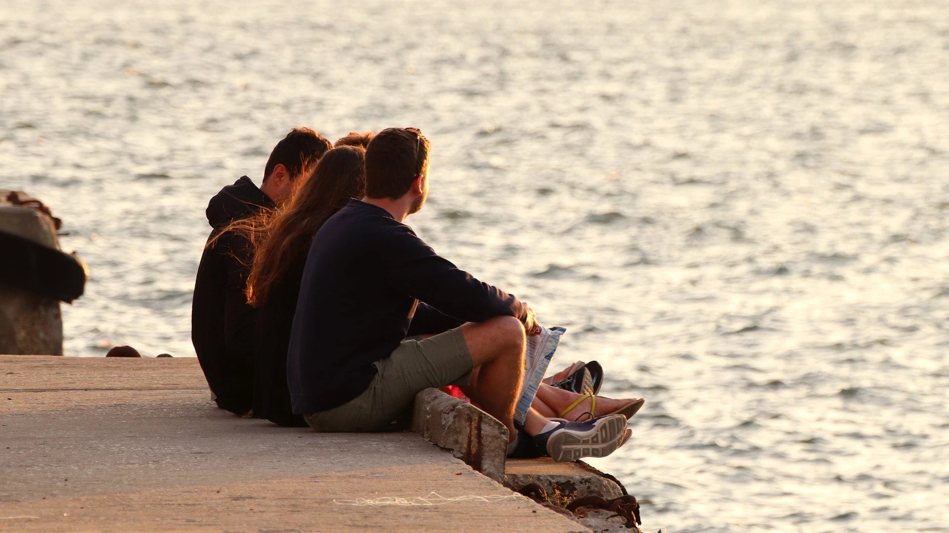 Un grupo de jóvenes charla al atardecer en una playa