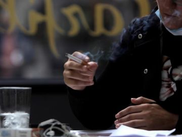 Una mujer fuma en una terraza. Una mujer fuma en una terraza.