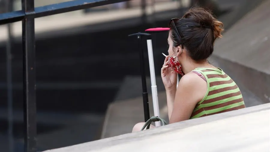 Una mujer fuma en la calle.