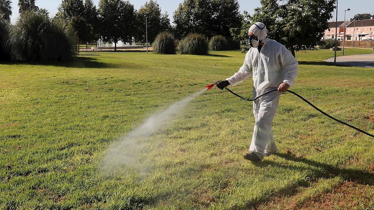  Un operario fumiga unos jardines en Coría del Río