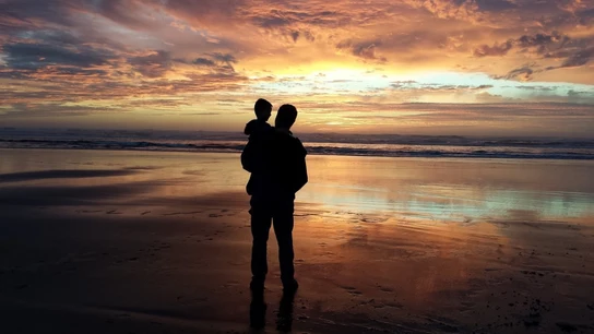 Un adulto y un niño frente a la playa Un adulto y un niño frente a la playa
