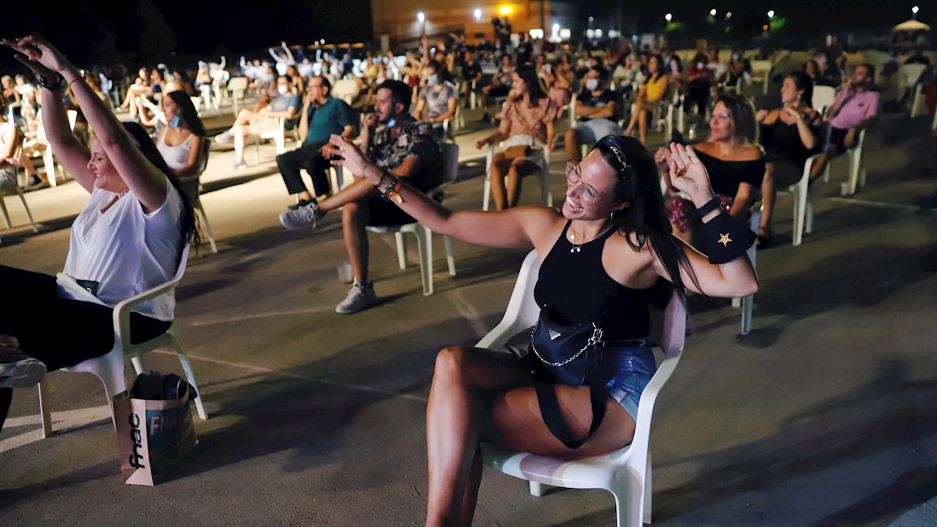 Jóvenes bailan sentados en el festival "Live Mar Menor" guardando la distancia
