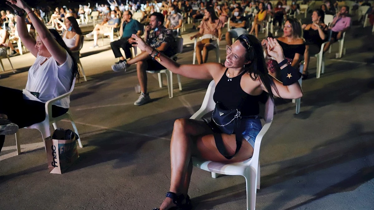 Jóvenes bailan sentados en el festival "Live Mar Menor" guardando la distancia