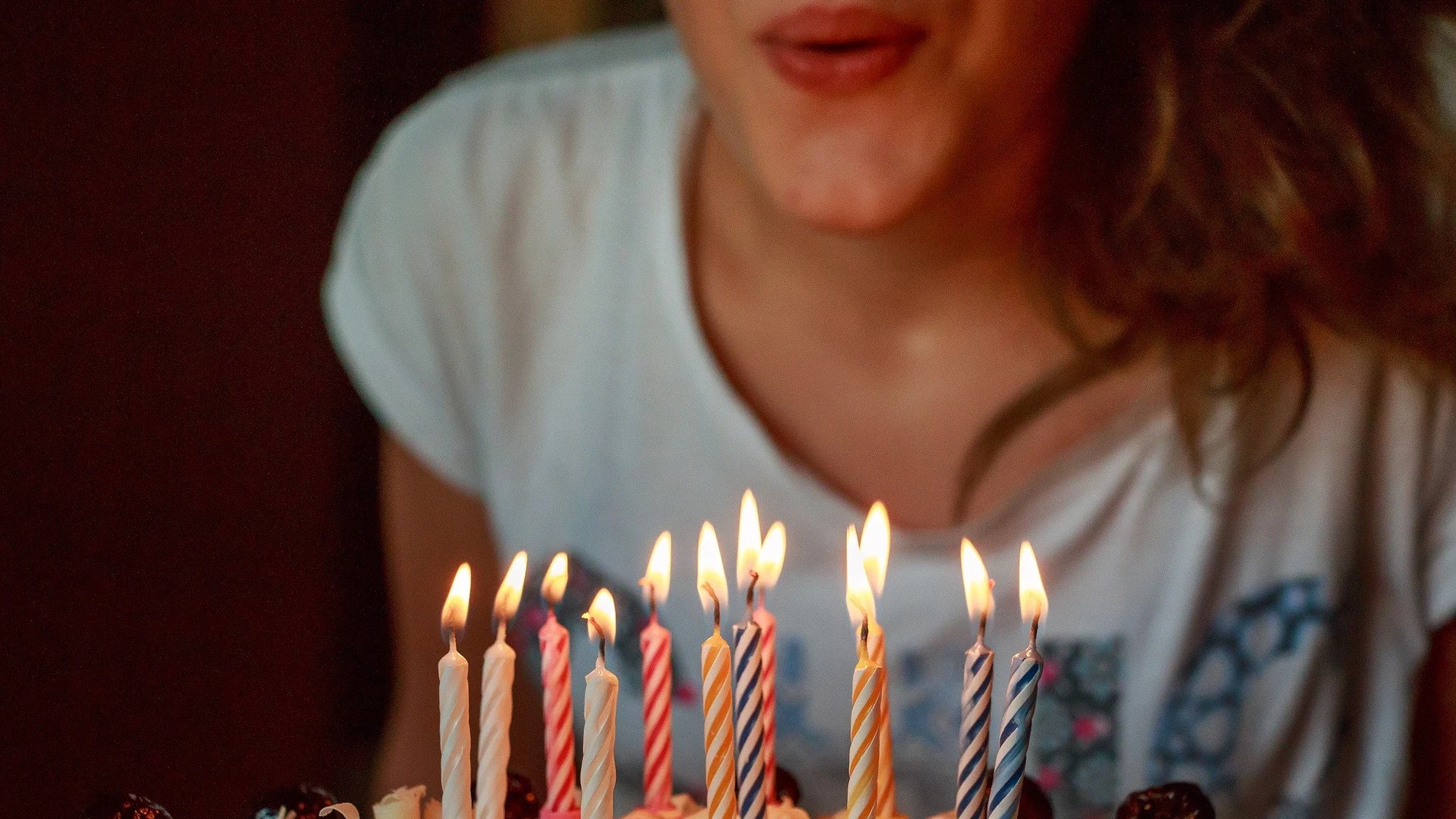 Imagen de archivo de una joven soplando las velas de una tarta