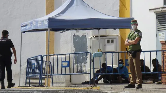 Un policía y un guarida de seguridad vigilan a un grupo de migrantes que consiguió saltar la valla. Un policía y un guarida de seguridad vigilan a un grupo de migrantes que consiguió saltar la valla.