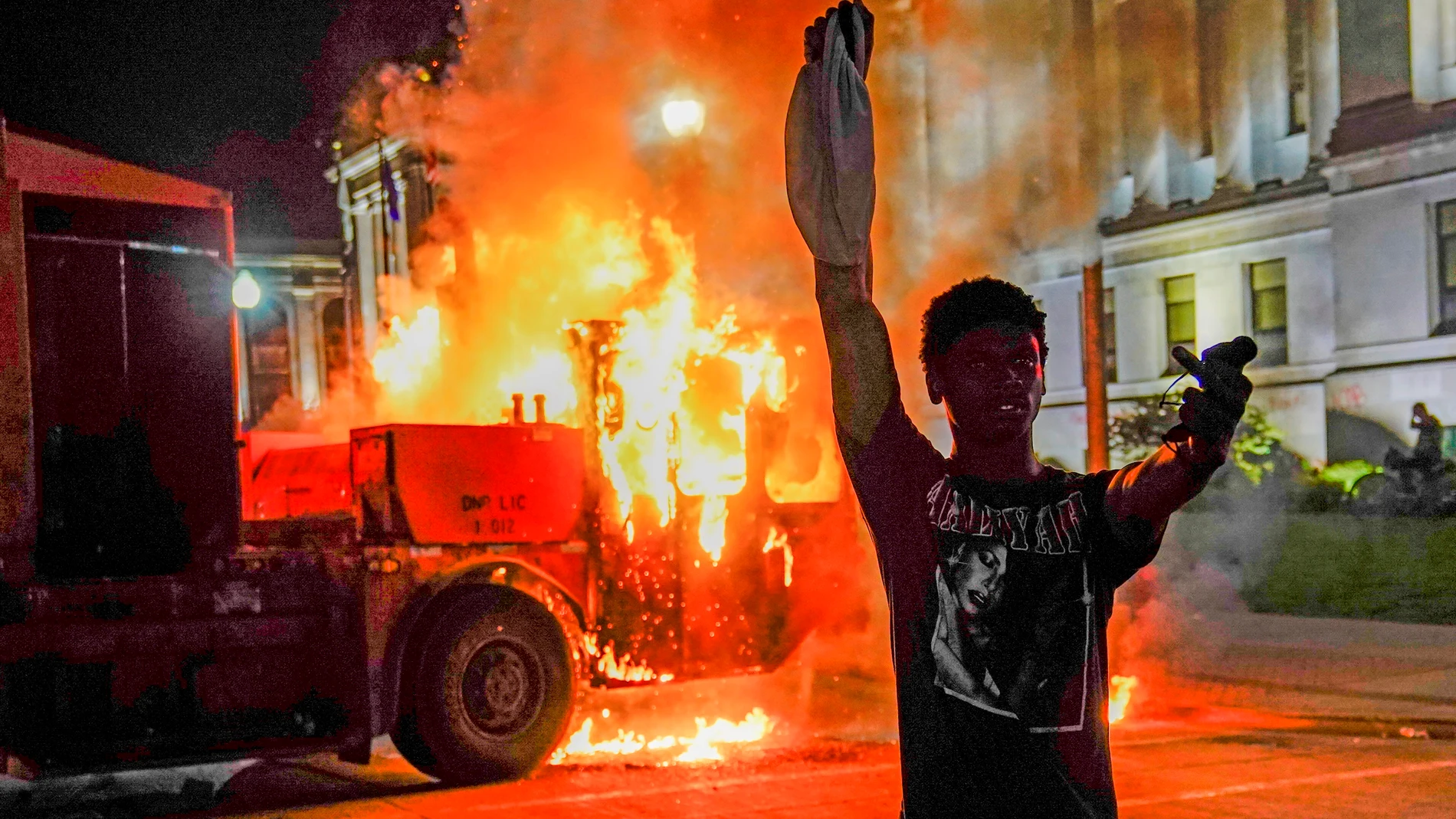 Un manifestante posa delante de un camión de basura en llamas durante la segunda noche de disturbios por los disparos a Jacob Blake en Kenosha, Wisconsin, EE. UU.
