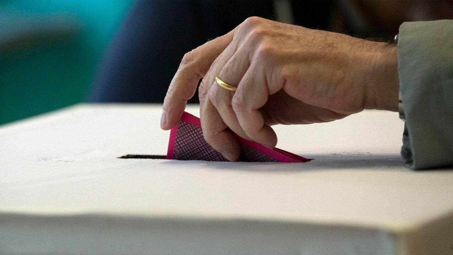 Una persona deposita su voto en una urna