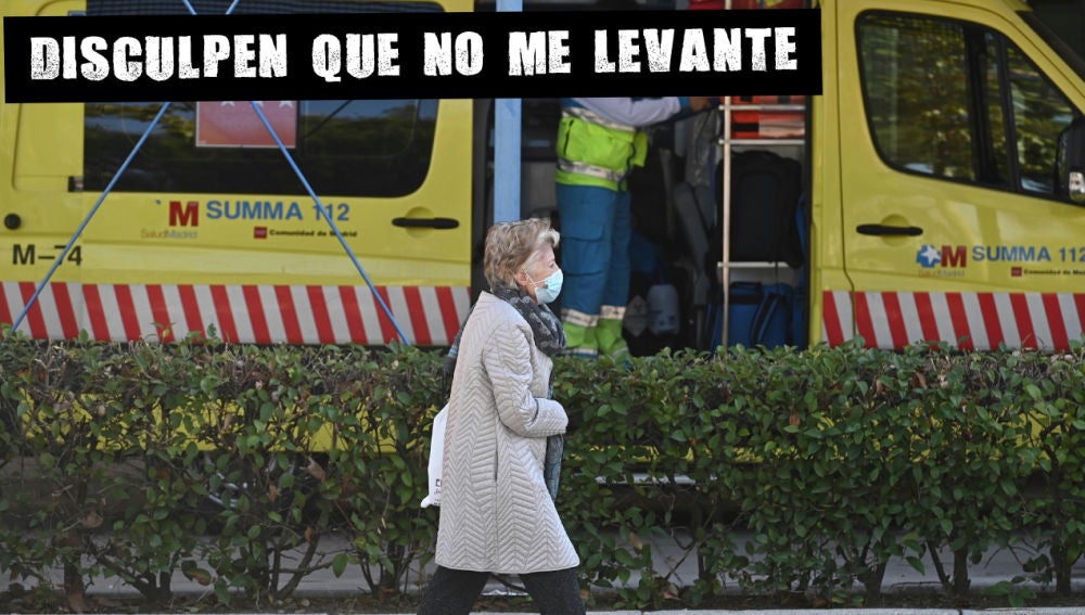 Una mujer pasa ante una ambulancia situada en el barrio de García Noblejas, en el distrito madrileño de Ciudad Lineal