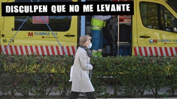 Una mujer pasa ante una ambulancia situada en el barrio de García Noblejas, en el distrito madrileño de Ciudad Lineal
