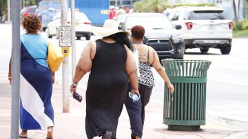 Imagen de tres personas con sobrepeso caminando por la calle