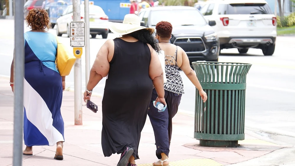 Imagen de tres personas con sobrepeso caminando por la calle