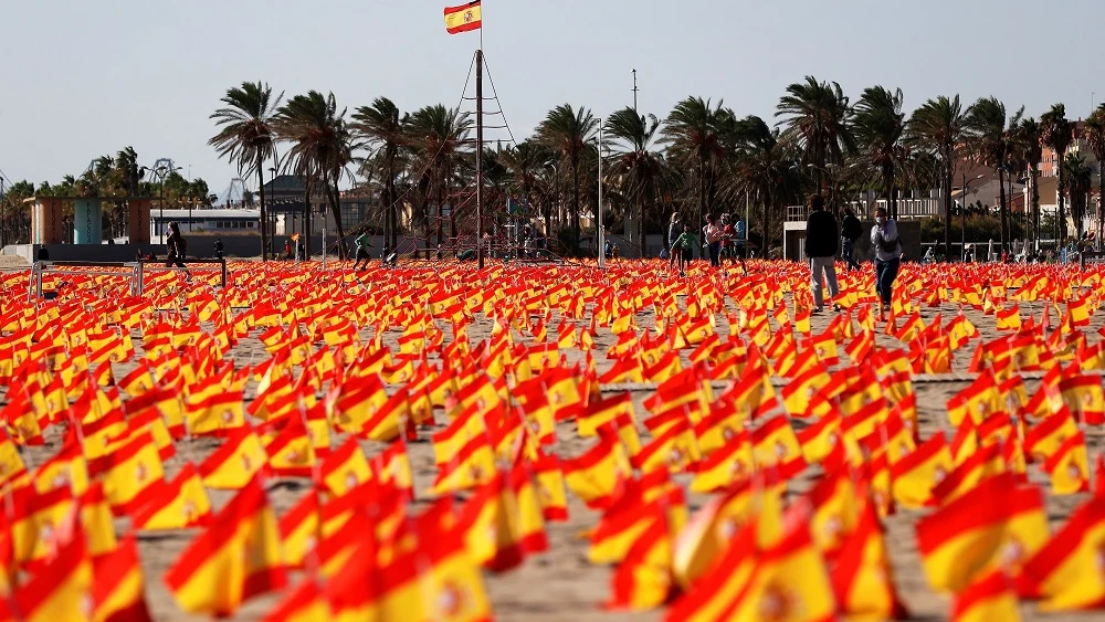 Imagen de las banderas colocadas en una playa de Valencia en homenaje a las víctimas del COVID-19