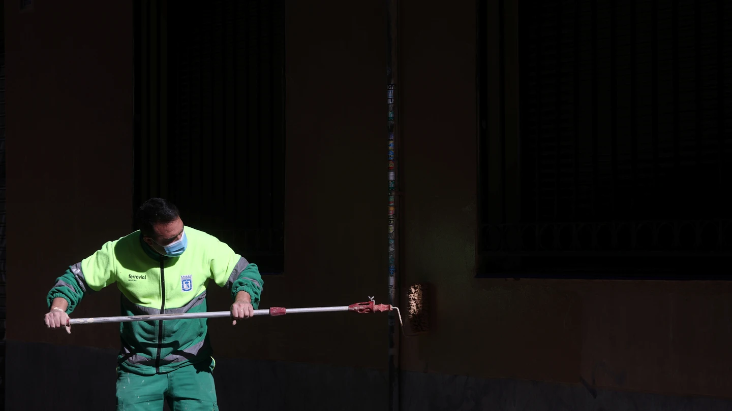 Un trabajador municipal pinta una pared Un trabajador municipal pinta una pared