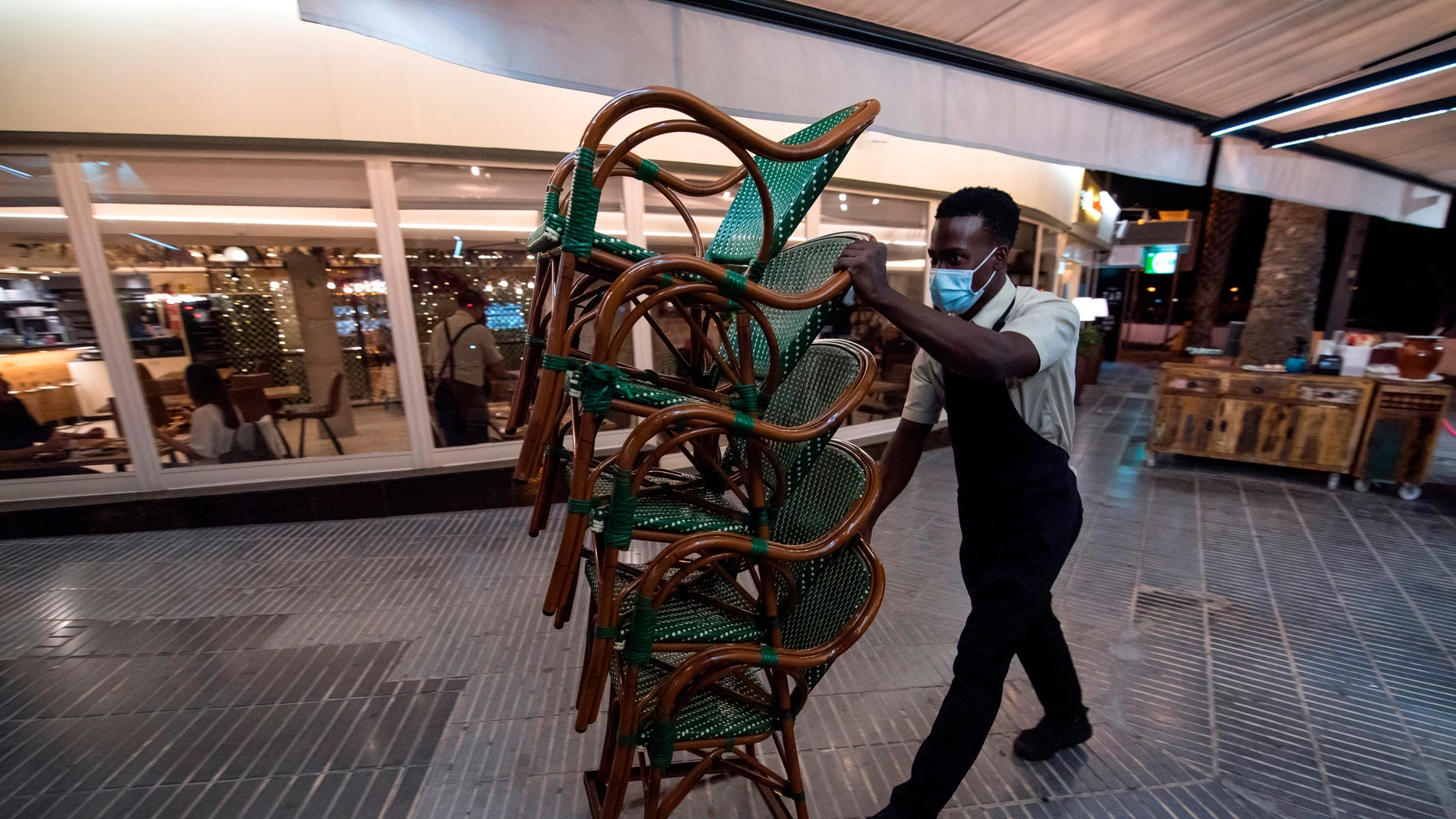 Un hostelero recoge el mobiliario de su terraza en Mallorca