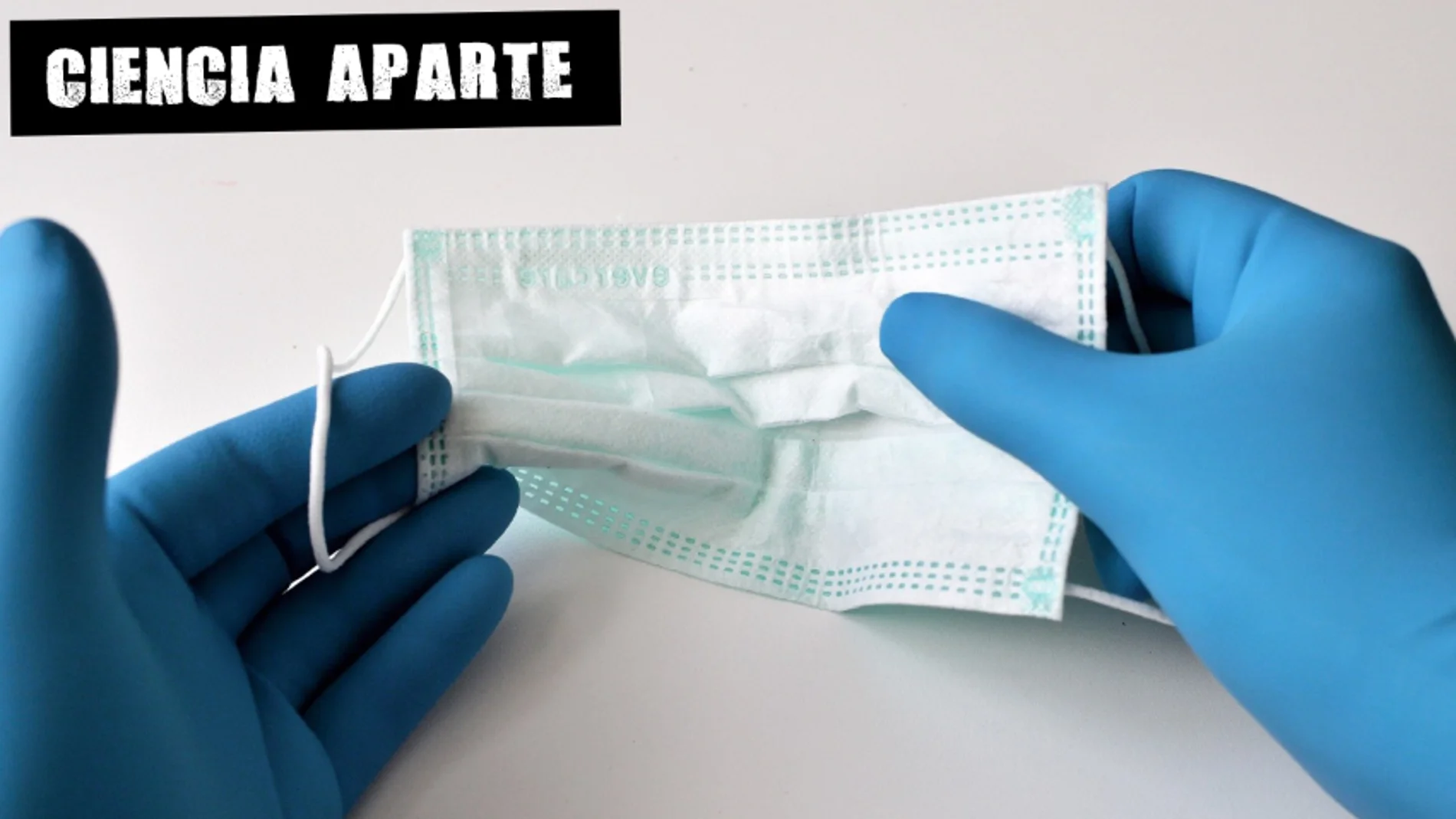 Unas manos con guantes sujetan una mascarilla Unas manos con guantes sujetan una mascarilla