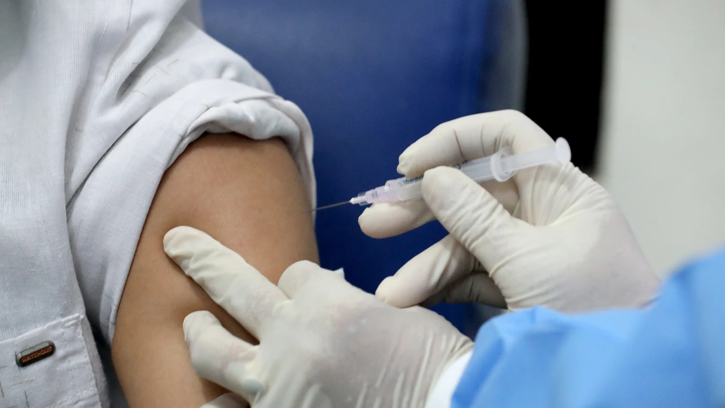 Un sanitario administra una vacuna a un paciente Un sanitario administra una vacuna a un paciente