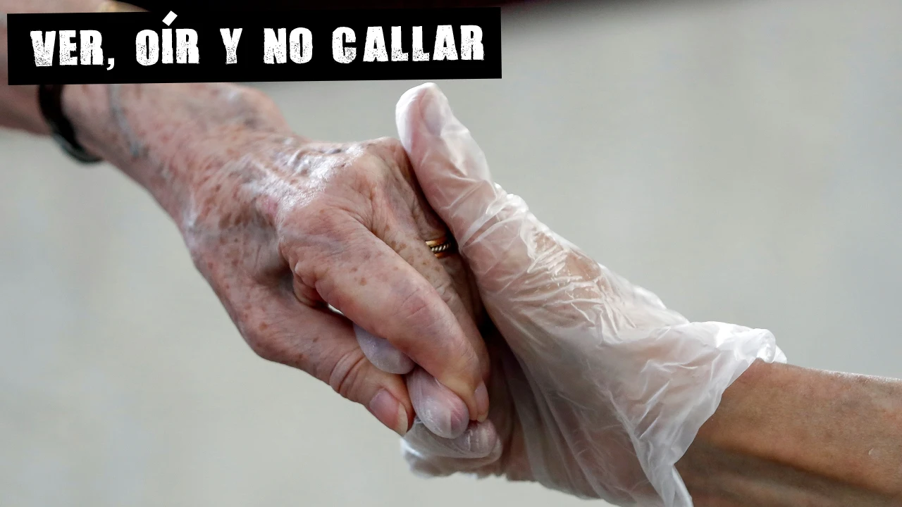 Una sanitaria sostiene la mano de una anciana