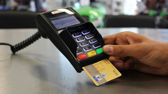 Una persona usa su tarjeta de crédito para una de sus compras. Una persona usa su tarjeta de crédito para una de sus compras.
