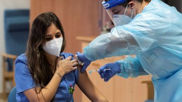 Imagen de una sanitaria mientras le inyectan la vacuna