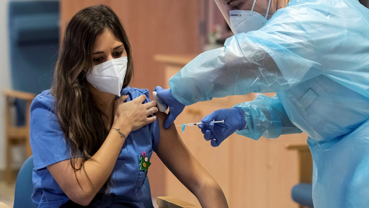 Imagen de una sanitaria mientras le inyectan la vacuna