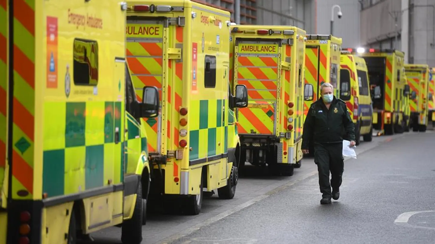 Un sanitario camina junto a una hilera de ambulancias en el Royal London Hospital Un sanitario camina junto a una hilera de ambulancias en el Royal London Hospital