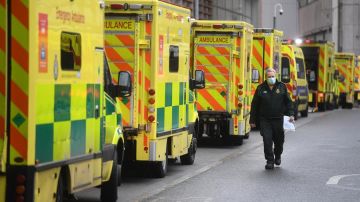 Un sanitario camina junto a una hilera de ambulancias en el Royal London Hospital