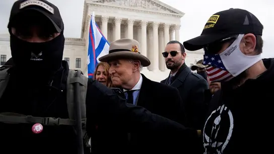 El exasesor y amigo personal de Trump Roger Stone, protegido por miembros de seguridad que llevan gorras de la milicia de Oath Keepers, en una de las concentraciones en Washington D.C. en los días previos a la ratificación de la victoria de Joe Biden. El exasesor y amigo personal de Trump Roger Stone, protegido por miembros de seguridad que llevan gorras de la milicia de Oath Keepers, en una de las concentraciones en Washington D.C. en los días previos a la ratificación de la victoria de Joe Biden.