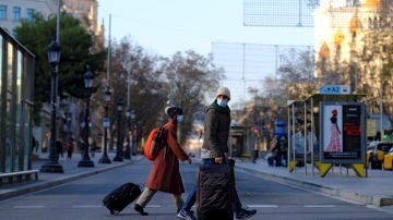 Una pareja pasea portando sus maletas