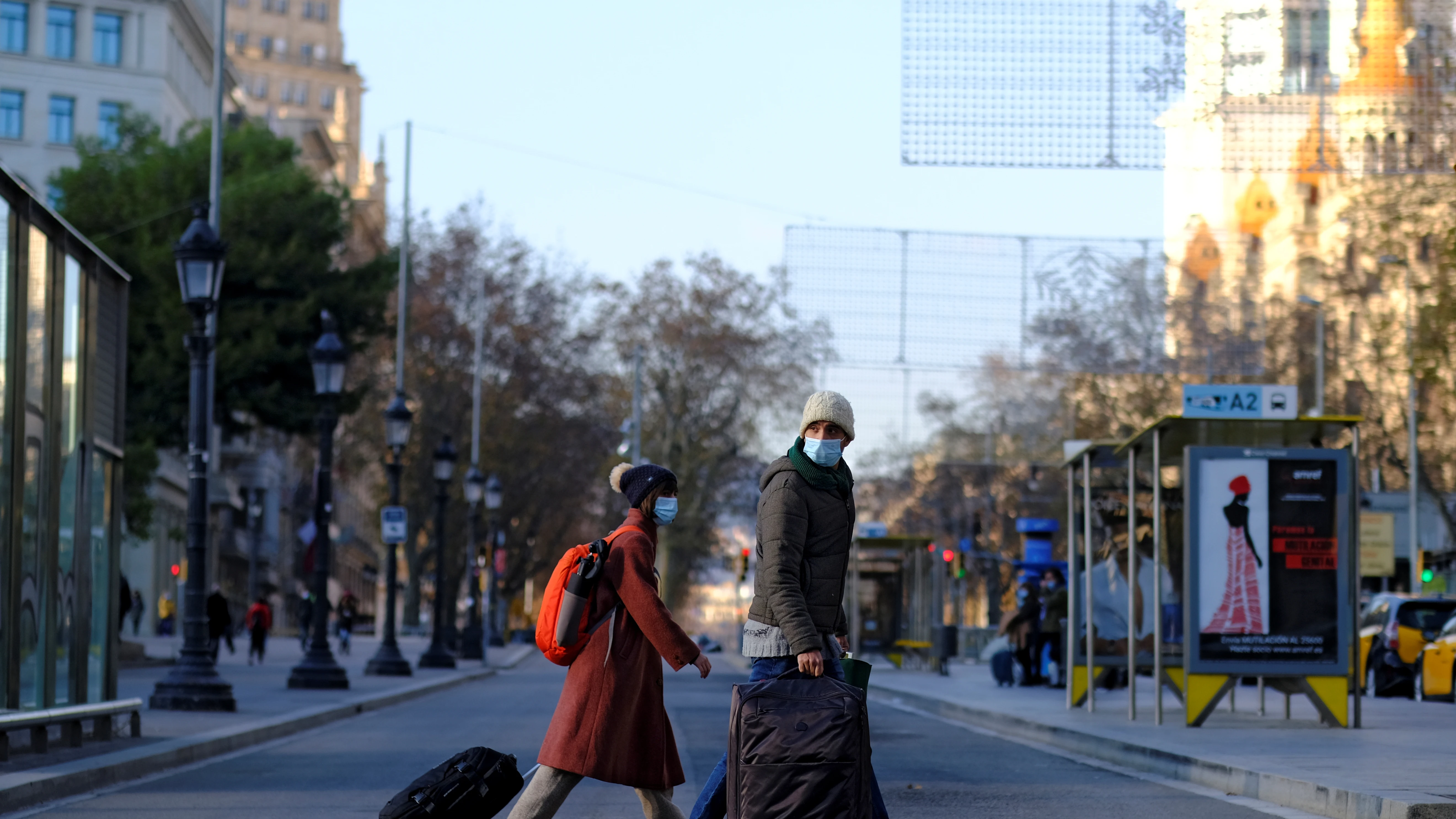 Una pareja pasea portando sus maletas