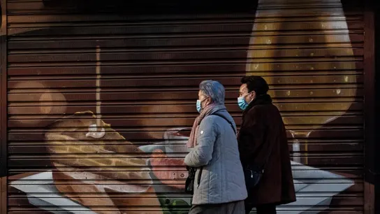 Personas caminan frente a un establecimiento cerrado Personas caminan frente a un establecimiento cerrado