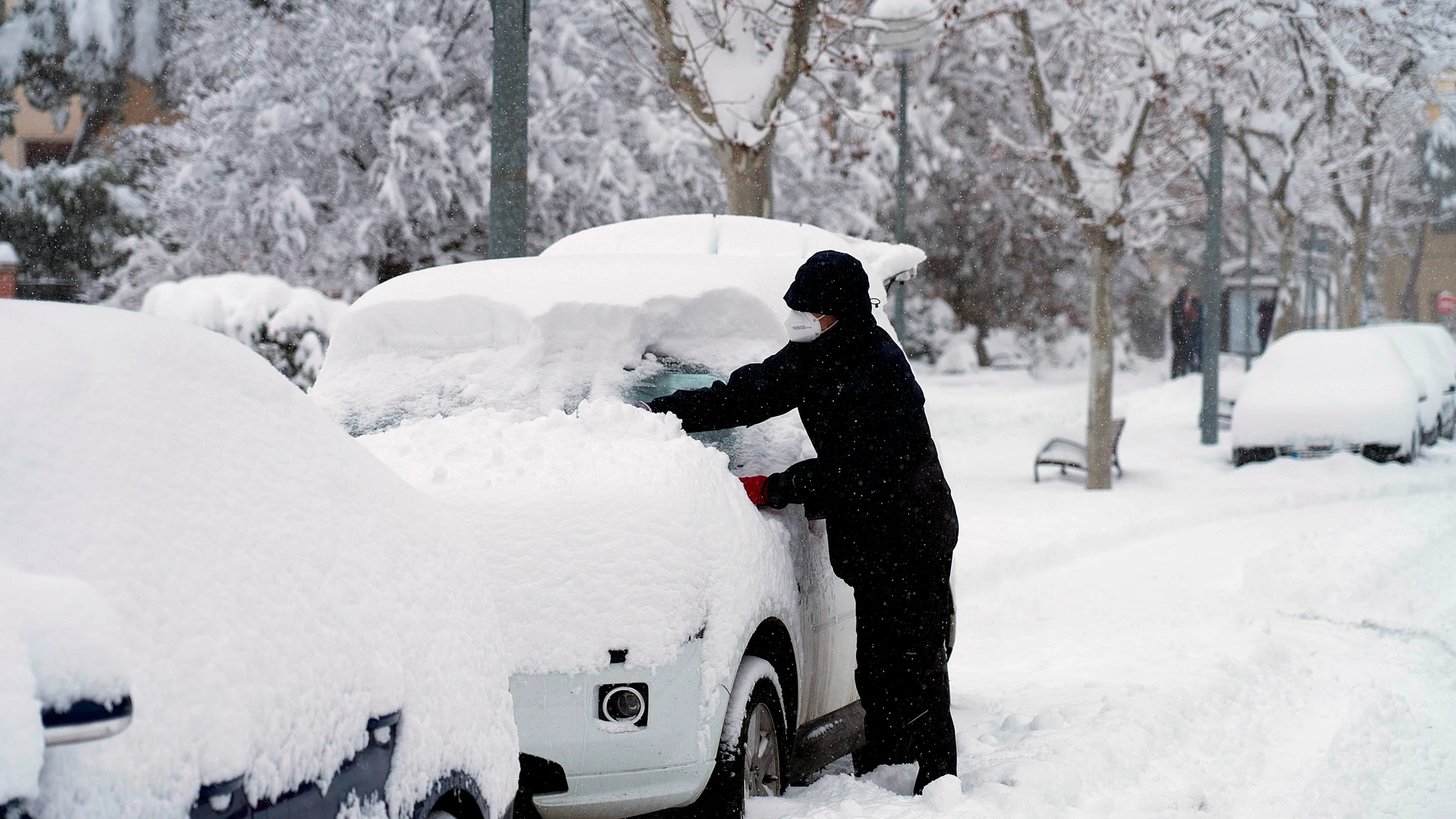 Un hombre quita la nieve de su coche