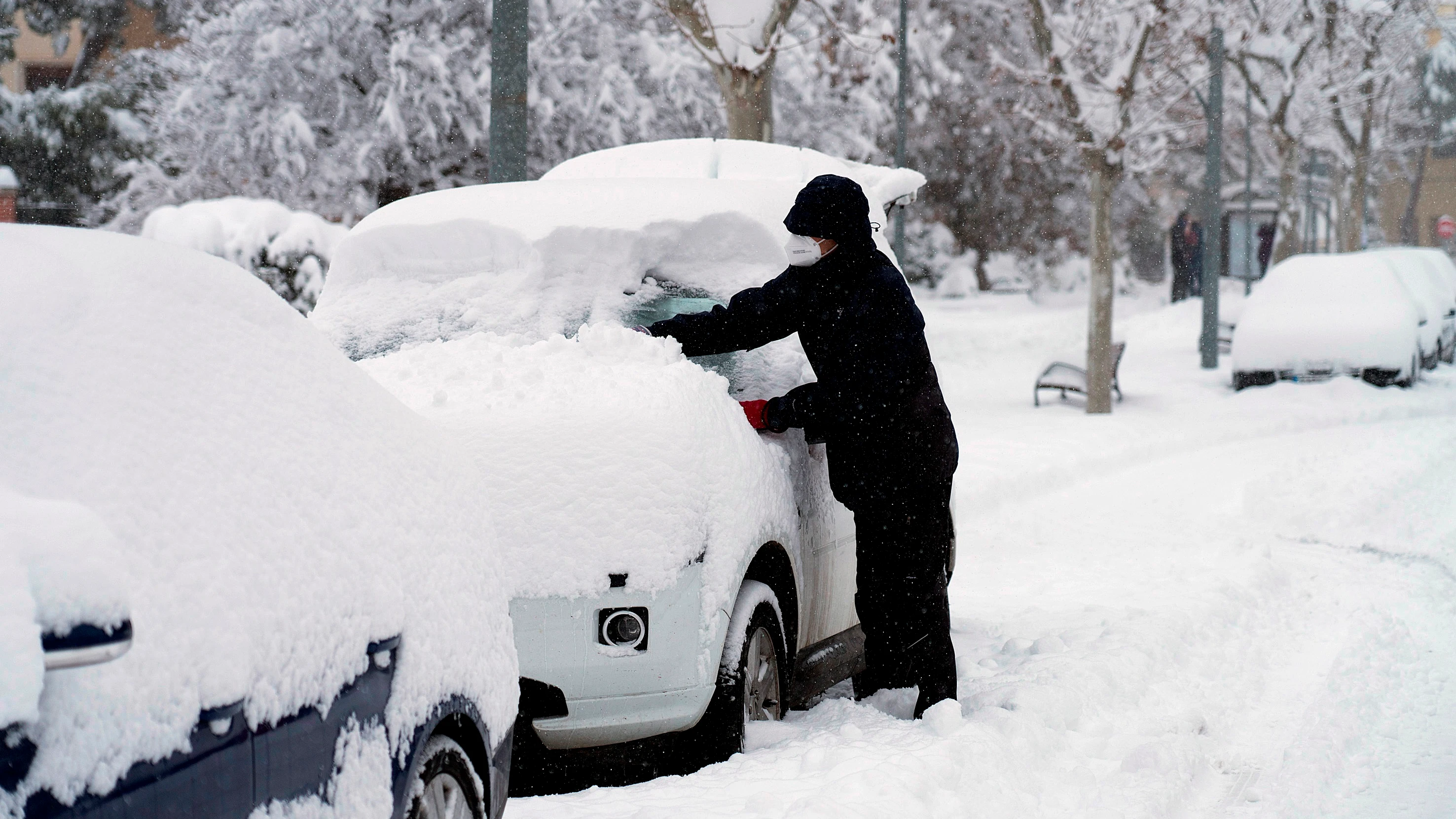 Un hombre quita la nieve de su coche