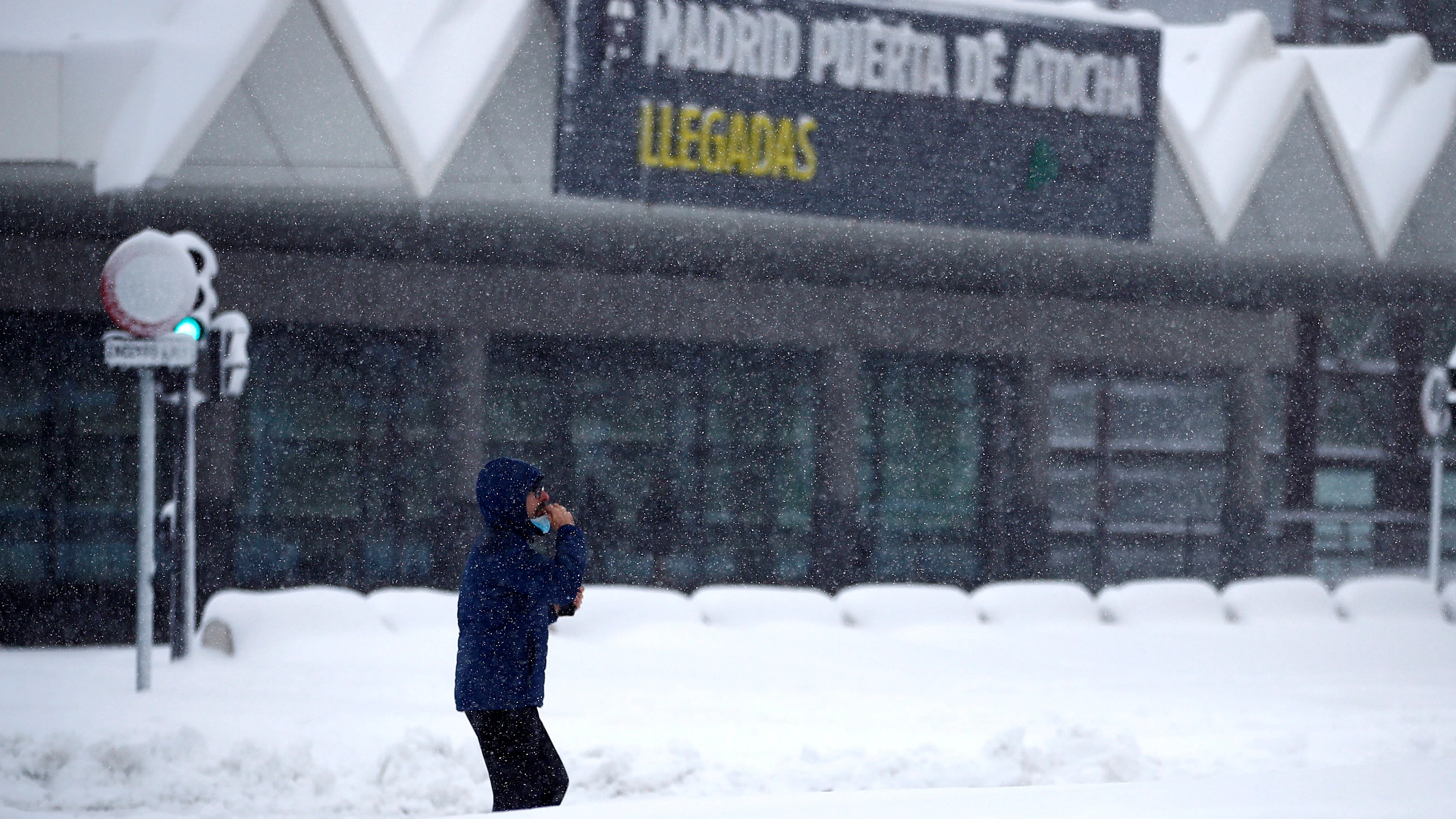 Un hombre espera en la estación de Atocha bajo la nieve