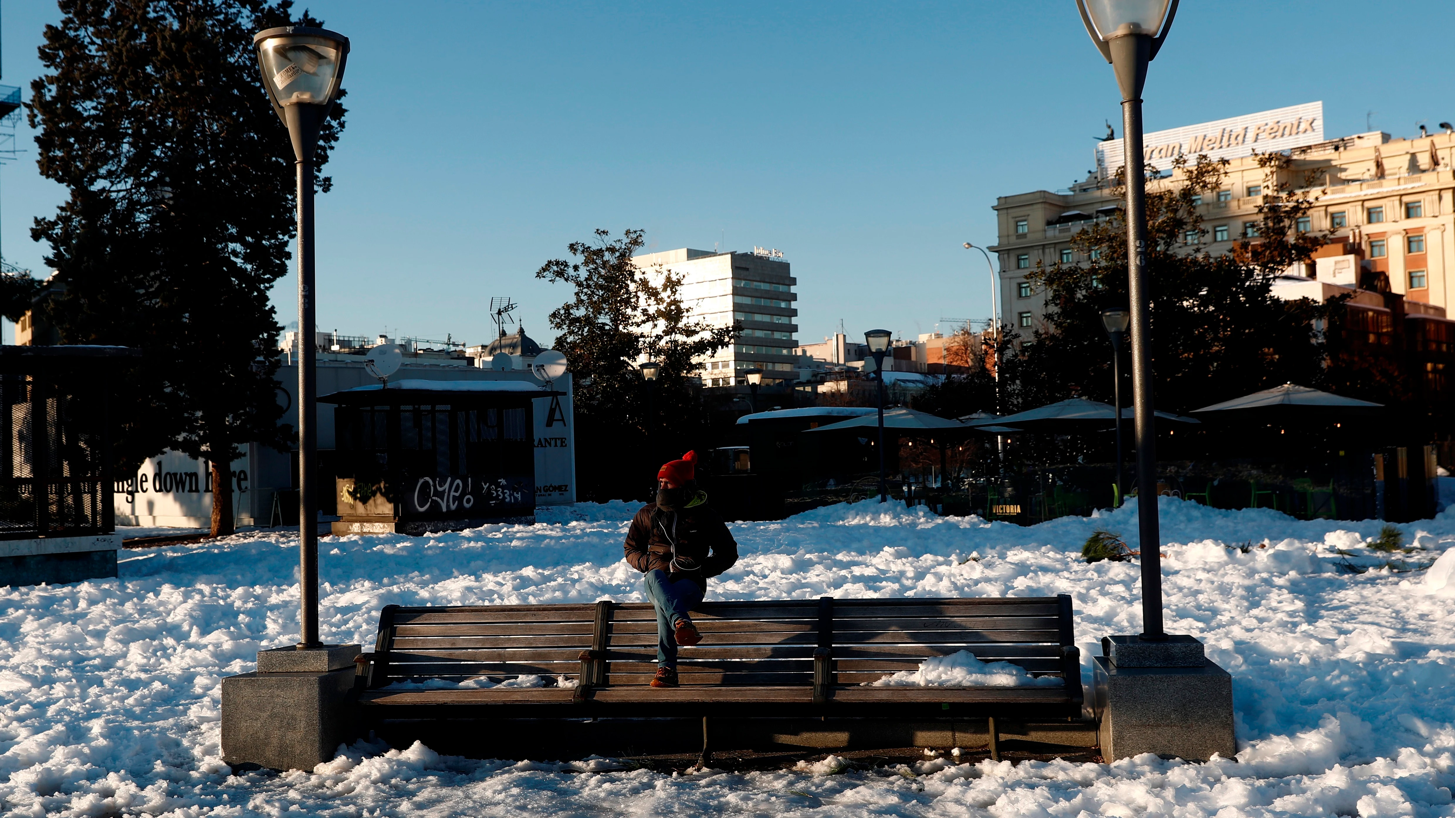 Un hombre sentado en un banco, rodeado de nieve este lunes en la plaza de Colón de Madrid