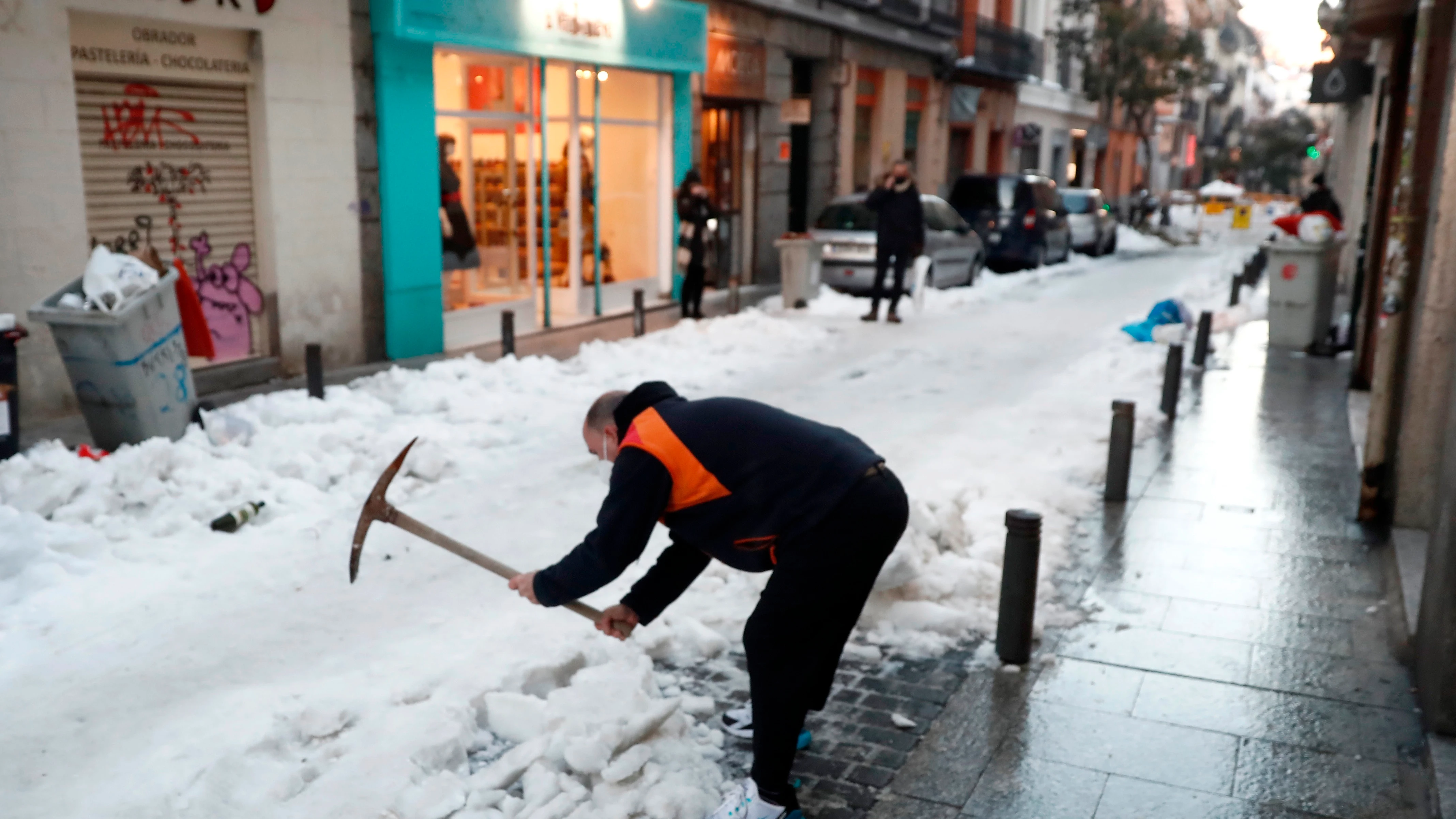 Un vecino retira nieve de la calzada en calle León de Madrid. 