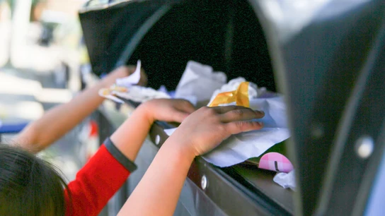 Un grupo de niños y niñas, reciclando un contenedor azul de papel y cartón Un grupo de niños y niñas, reciclando un contenedor azul de papel y cartón