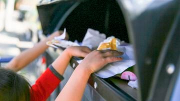 Un grupo de niños y niñas, reciclando un contenedor azul de papel y cartón