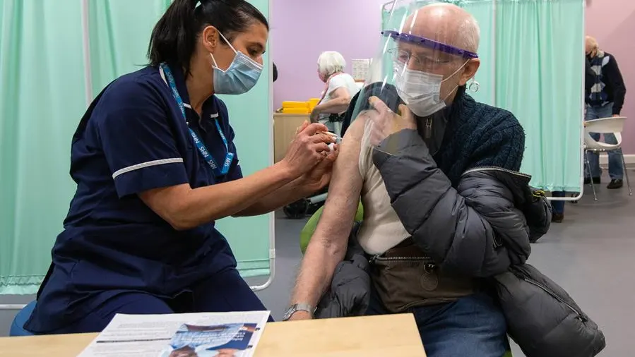 Una sanitaria vacuna a un hombre en Reino Unido